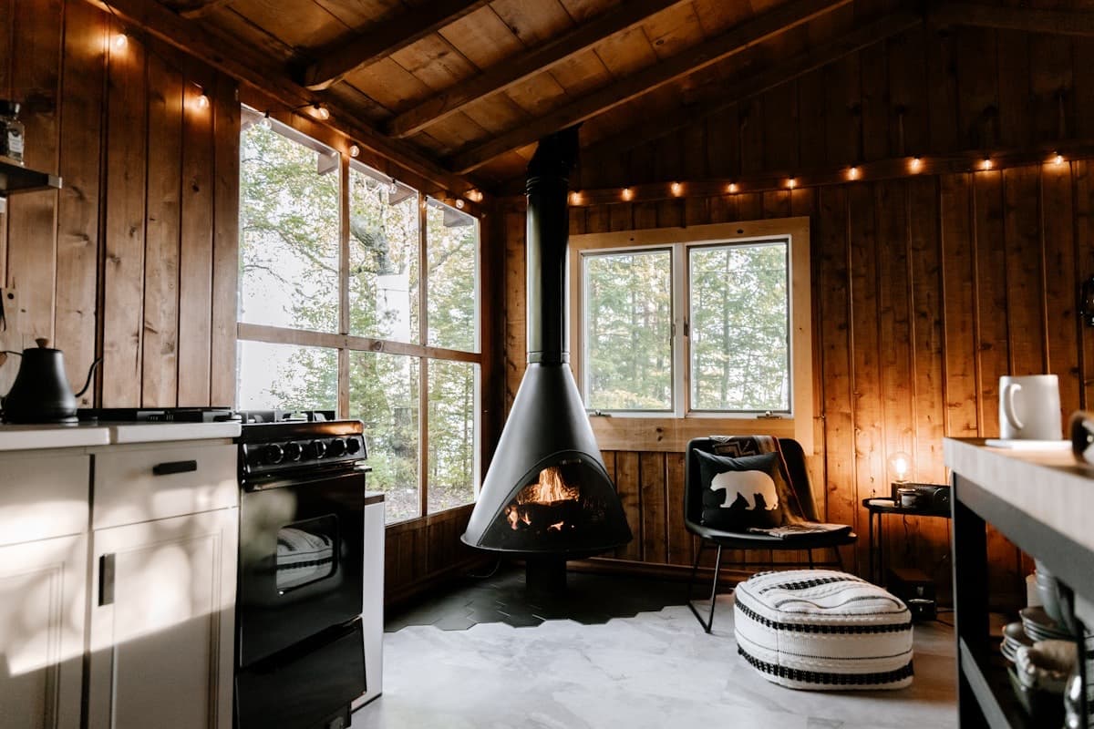 A snug sitting room with a wood-burning stove, timber walls and warm lamplight